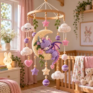 May include: A crochet baby mobile featuring a central cream-colored crescent moon with a sleeping purple dragon, surrounded by hanging white clouds, purple and pink stars, heart shapes, and spheres, all suspended from a circular wooden frame.