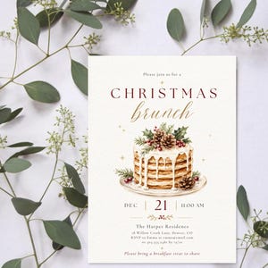 Op de afbeelding: Een rechthoekige uitnodigingskaart met de tekst "CHRISTMAS brunch" in donkerrood en goudkleurig schrift. In het midden staat een aquarelillustratie van een stapel pannenkoeken met wit glazuur, dennentakken en dennenappels op een bord.