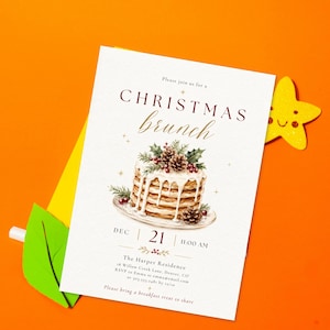 Op de afbeelding: Een witte rechthoekige uitnodigingskaart voor een kerstbrunch met een aquarelillustratie van een stapel pannenkoeken gegarneerd met hulst en dennenappels. De tekst luidt: Please join us for a CHRISTMAS brunch, DEC 21, 11:00 AM, The Harper Residence.