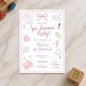 May include: A rectangular invitation card with a scalloped pink border featuring illustrations of pyjamas, a bow, a sleep mask, nail polish, cucumber slices, a disco ball, face cream, a mirror, and slippers. Text reads: Spa Jamma Party! Olivia's 8th Birthday!