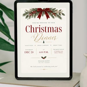 May include: A digital Christmas dinner invitation displayed on a tablet screen. The design features a red velvet bow, pine branches, and holly berries at the top. Text includes: You're invited to our Christmas Dinner, Dec 20, 6:00 P.M.