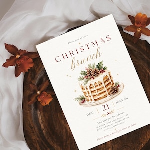 Op de afbeelding: Een rechthoekige uitnodigingskaart voor een kerstbrunch met een aquarelillustratie van een stapel pannenkoeken gegarneerd met dennenappels en hulst. De tekst luidt: Please join us for a CHRISTMAS brunch, DEC 21, 11:00 AM, The Harper Residence.