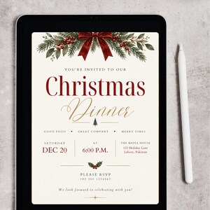 May include: A digital tablet displaying a Christmas dinner invitation with a cream background, red bow, and pine branch graphics. The text reads: You're invited to our Christmas Dinner, Saturday Dec 20, 6:00 P.M., The Maple House, 123 Holiday Lane, Lahore, Pakistan.