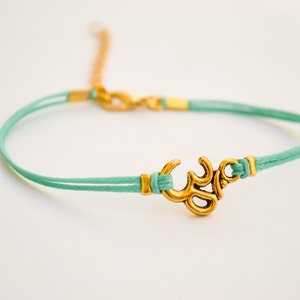 Blågrönt Om-armband: Guldfärgad hinduisk symbolberlock