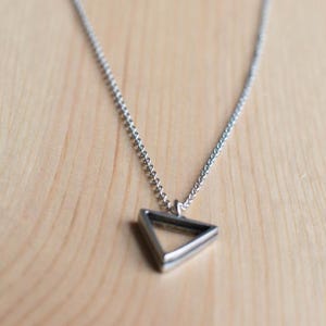 May include: A silver chain necklace with a geometric triangle pendant.