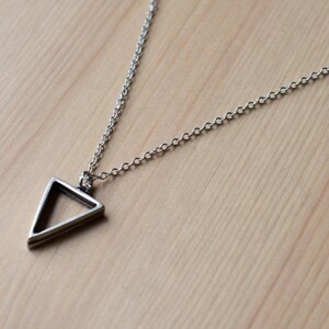 May include: A silver chain necklace with a simple, geometric triangle pendant.
