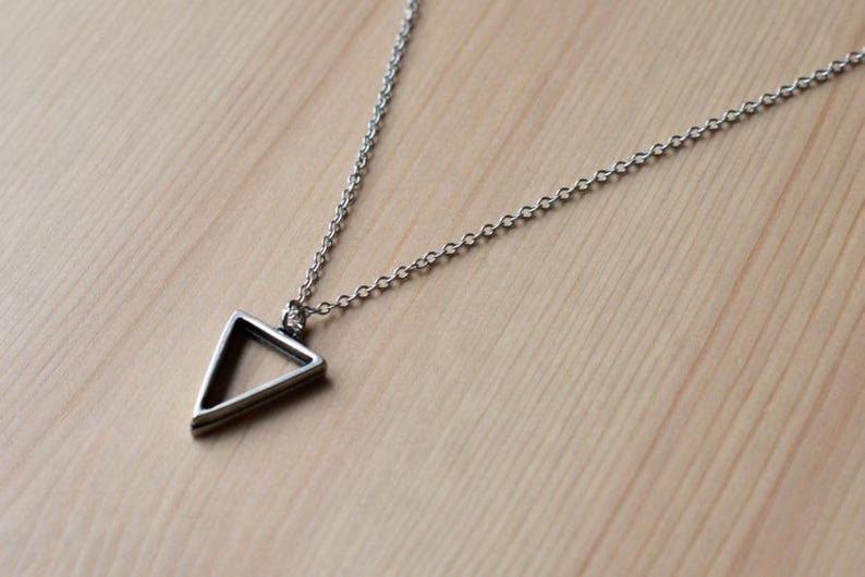 May include: A silver chain necklace with a simple, geometric triangle pendant.