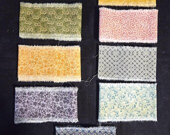 Könnte beinhalten: Neun Stoffmuster mit verschiedenen floralen und geometrischen Mustern. Farben sind Blau, Gelb, Rosa, Grün und Lila. Jedes Muster hat einen ausgefransten Rand und ist auf einer schwarzen Oberfläche angeordnet.