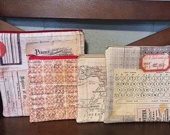 May include: Four rectangular fabric pouches with zip closures, featuring vintage-style prints including a Perfect Attendance certificate, a red patterned ledger, a map of the Pacific Ocean, and a typewriter keyboard layout with various text elements.