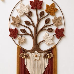 Peut inclure: Une décoration murale en macramé composée d'un cadre circulaire marron avec un arbre central. Les branches sont ornées de feuilles en forme d'érable aux tons crème, marron et rouille. Une frange en V crème et rouille pend sous l'arbre.