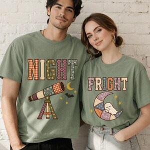May include: Two sage green t-shirts featuring patchwork-style graphics. The left shirt displays the word NIGHT with a telescope, moon, and bat. The right shirt displays the word FRIGHT with a crescent moon and a small ghost character.
