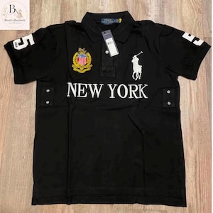 May include: A black short-sleeved polo shirt featuring a white embroidered polo player logo, the text NEW YORK in white, a crest with a shield, and the number 5 on the sleeves. It includes a collar, a button placket, and a hanging product tag.