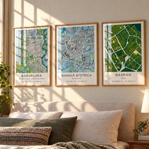 May include: Three framed wall art prints featuring detailed city maps of Banjaluka, Bosnia and Herzegovina; Banská Bystrica, Slovakia; and Basrah, Iraq. Each print includes the city name, country, and geographic coordinates in black text.