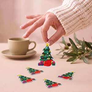 May include: A set of embroidered Christmas tree patches featuring a green tree with colourful ornaments, a yellow star topper, and red and blue gift boxes at the base. The patches are shaped like triangular trees with detailed stitching throughout.