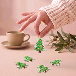 May include: A set of embroidered Christmas tree patches featuring green foliage, a brown trunk, and colorful ornaments. Each patch is shaped like a pine tree with white snow accents on the branches, designed for fabric application.