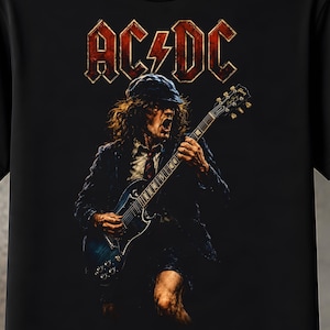 Puede incluir: Una camiseta negra con un estampado gráfico de un guitarrista con gorra y traje, tocando una guitarra eléctrica azul oscuro. Sobre la figura, el nombre de la banda AC/DC está impreso en una fuente roja desgastada con un rayo en el centro.