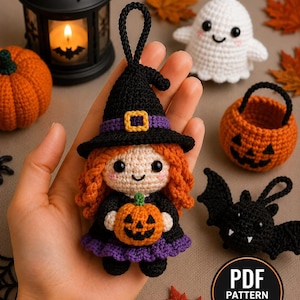 Puede incluir: Un adorno de muñeca de ganchillo con pelo naranja, un sombrero de bruja negro con una banda morada y un vestido negro con falda morada. La muñeca sostiene una pequeña calabaza naranja. Una insignia circular muestra el texto PDF PATTERN IN ENGLISH.