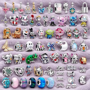 May include: A collection of assorted metal and enamel charms featuring various cartoon characters, animals, butterflies, flowers, and decorative shapes, including a silver padlock, a coffee cup, and several colorful glass beads with metallic accents.