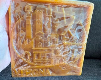 May include: A square, amber-colored block of wax featuring a detailed relief sculpture of the city of Verona, Italy. The design includes architectural towers and buildings, with the word VERONA embossed in capital letters at the bottom.