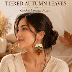 May include: Tiered autumn leaves crochet earrings pattern. The earrings feature a vertical arrangement of three crocheted leaf shapes in cream, sage green, and burnt orange, suspended from a gold-toned metal hook and a small circular ring.