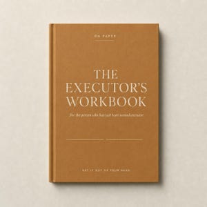 Puede incluir: Un libro de tapa dura de color beige titulado The Executor's Workbook. La portada presenta el texto ON PAPER en la parte superior, el título principal en letras blancas grandes y el subtítulo For the person who has just been named executor. GET IT OUT OF YOUR HEAD está en la parte inferior.