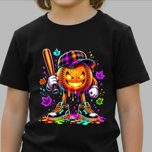 May include: A black t-shirt featuring a graphic of a glowing orange jack-o'-lantern baseball character wearing a plaid cap and high-top trainers. The character holds a baseball bat, surrounded by colourful paint splatters and autumn leaves.