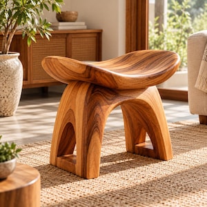 May include: A wooden stool featuring a curved, saddle-shaped seat and four thick, arched legs. The stool is crafted from light brown wood with a prominent, swirling grain pattern visible throughout the entire structure, showcasing natural wood tones.