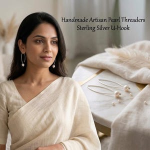 May include: Sterling silver U-hook threader earrings featuring a single white pearl on each end. The text Handmade Artisan Pearl Threaders Sterling Silver U-Hook is visible. These earrings have a curved, elongated wire design.