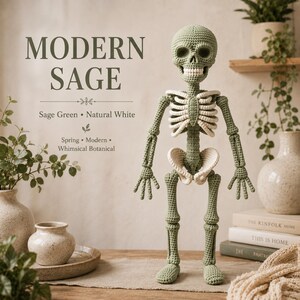 Detailed crochet skeleton figure with a rounded skull and clearly defined eye sockets, nose cavity, jaw, and individual teeth. Below the head, the cream crocheted rib cage, central sternum, spine, abdominal vertebrae, pelvis, arms, hands, legs, and feet are arranged in a recognizable skeletal form. Fine yarn texture is visible throughout, creating a detailed amigurumi skeleton design.
