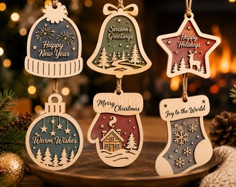 May include: Six wooden holiday ornaments hanging by twine. Shapes include a beanie with 'Happy New Year', a bell with 'Season's Greetings', a star with 'Happy Holidays', a round bauble with 'Warm Wishes', a mitten with 'Merry Christmas', and a stocking with 'Joy to the World'.