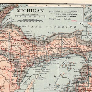 Pode incluir: Um mapa impresso de estilo antigo de Michigan, focado na pen&iacute;nsula superior e &aacute;reas circundantes. O mapa apresenta terra bege, &aacute;gua azul e linhas vermelhas para ferrovias. Inclui uma escala de milhas e quil&ocirc;metros, al&eacute;m de um mapa inserido.