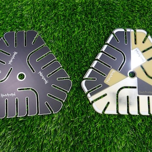 May include: Two triangular, decorative objects with a central hole and cut-out designs. One is black with white trim, the other is silver, gold, and black. The text "Ribs Are Red" is printed on both.