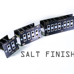 Pu&ograve; includere: Tre moduli elettronici neri con testo bianco e un motivo a stelle. I moduli hanno pi&ugrave; fori e sono etichettati "Patch Bae". Il testo "SALT FINISH" &egrave; visualizzato sotto i moduli.