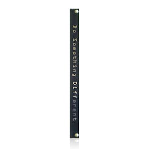 May include: A long, narrow, rectangular black metal strip featuring the text "Do Something Different." printed in a light, sans-serif font. The strip has a small, circular hole at both the top and bottom ends, designed for mounting or attachment purposes.