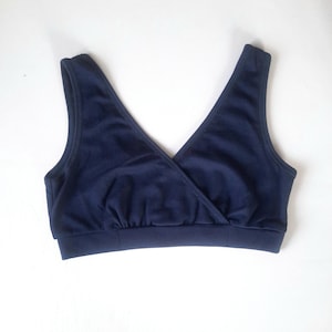 Op de afbeelding: Een donkerblauwe, mouwloze, cross-front bh met een brede band.
