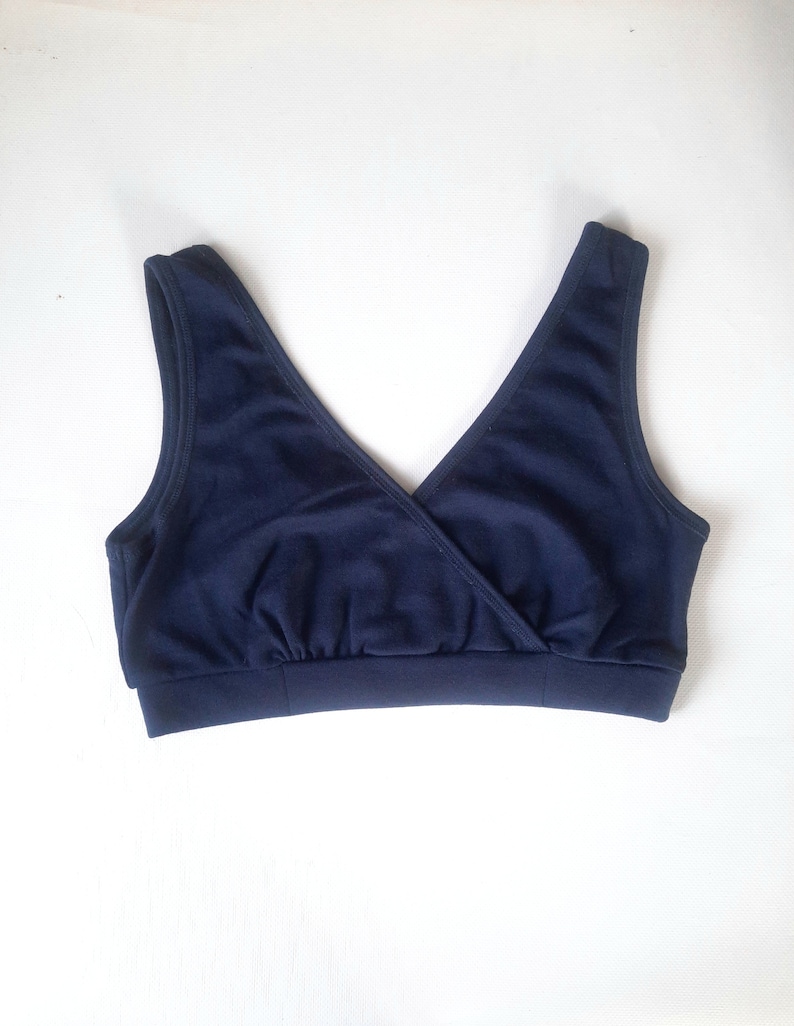 Op de afbeelding: Een donkerblauwe, mouwloze, cross-front bh met een brede band.