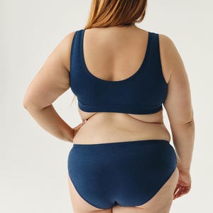 Op de afbeelding: Een donkerblauwe naadloze bh en bijpassende onderbroek. De bh heeft een ronde hals en de onderbroek heeft een hoge beenuitsnijding.