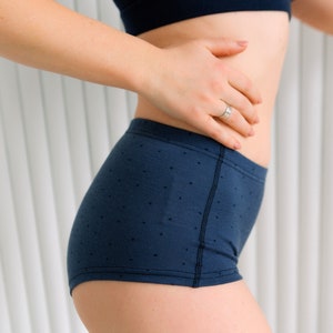 May include: A pair of dark blue underwear with a small white polka dot pattern. The underwear has a wide waistband and a comfortable fit.
