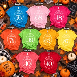 May include: A collection of nine short-sleeved crew neck t-shirts in various colors, each featuring a white oval graphic with the text Sol de Janeiro and a unique two-digit number, including 76, 68, 48, 71, 39, 62, 87, and 40.