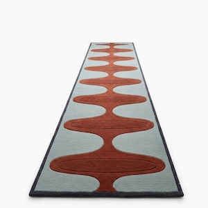 May include: A long rectangular runner rug featuring a repeating pattern of rust-colored oval shapes connected by a central vertical line against a light blue background, all framed by a dark gray border that defines the edges of the floor covering.