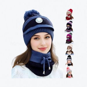 May include: A navy blue knit beanie with a matching pom-pom, a small circular vent, and a brim. The set includes a coordinating navy blue neck warmer with a drawstring tie. Additional colour variations are shown in a vertical column on the right.