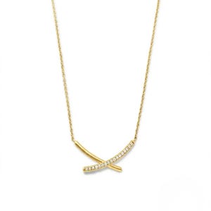 May include: A gold necklace featuring a pendant composed of two intersecting curved bars. One bar is smooth and polished gold, while the other is set with a row of small, clear, sparkling stones. The pendant hangs from a delicate gold chain.