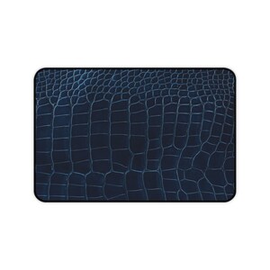 Può includere: Un tappetino rettangolare caratterizzato da una superficie blu navy scuro con una texture in rilievo ripetitiva che imita l'aspetto della pelle di alligatore o coccodrillo, definita da una griglia di squame irregolari e solchi profondi.