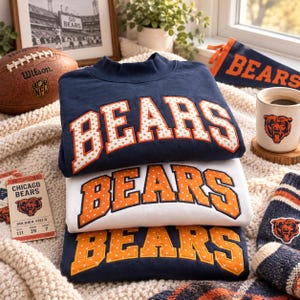 May include: A stack of three crewneck sweatshirts in navy blue, white, and navy blue. Each sweatshirt features the word BEARS in large, block-style letters with a polka dot pattern. The top and bottom sweatshirts are navy, while the middle is white.