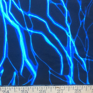 May include: Close-up of a black fabric with a blue and white lightning bolt pattern.