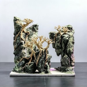 Könnte beinhalten: Eine dekorative Skulptur mit zerklüfteten, dunkelgrünen und grauen Felsformationen, über deren Oberflächen sich hellbraune, wurzelartige Strukturen ziehen. Das Objekt ist auf einer flachen, rechteckigen weißen Basis montiert.