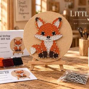 May include: A mini string art DIY kit featuring a fox design on a circular wooden board displayed on a small easel. The kit includes spools of white, orange, dark red, and black thread, a bag of metal nails, and an instruction card.
