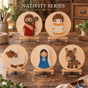 Könnte beinhalten: Fünf runde Holzschilder mit Fadenkunst-Motiven eines Hirten, eines Engels, eines Schafes, Maria und eines Esels. Jedes Schild steht auf einer kleinen Holzstaffelei. Der Text NATIVITY SERIES ist oben zentriert, mit Beschriftungen darunter.
