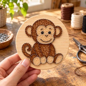 Könnte beinhalten: Eine kreisförmige Holzplatte mit einem Fadenkunst-Design eines Affen. Der Affe ist aus dunkelbraunem und hellbeigem Faden gefertigt, der um kleine Metallnägel gewickelt ist und eine detaillierte Figur mit geringeltem Schwanz bildet.