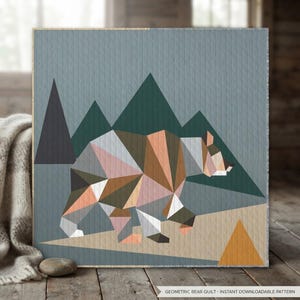 Könnte beinhalten: Ein quadratischer Quilt mit einem geometrischen Bärenmotiv aus dreieckigen Formen in Braun-, Rosa-, Weiß- und Grautönen. Der Hintergrund zeigt dunkelgrüne und anthrazitfarbene Bergsilhouetten vor einem blauen Himmel. Text: GEOMETRIC BEAR QUILT - INSTANT DOWNLOADABLE PATTERN.